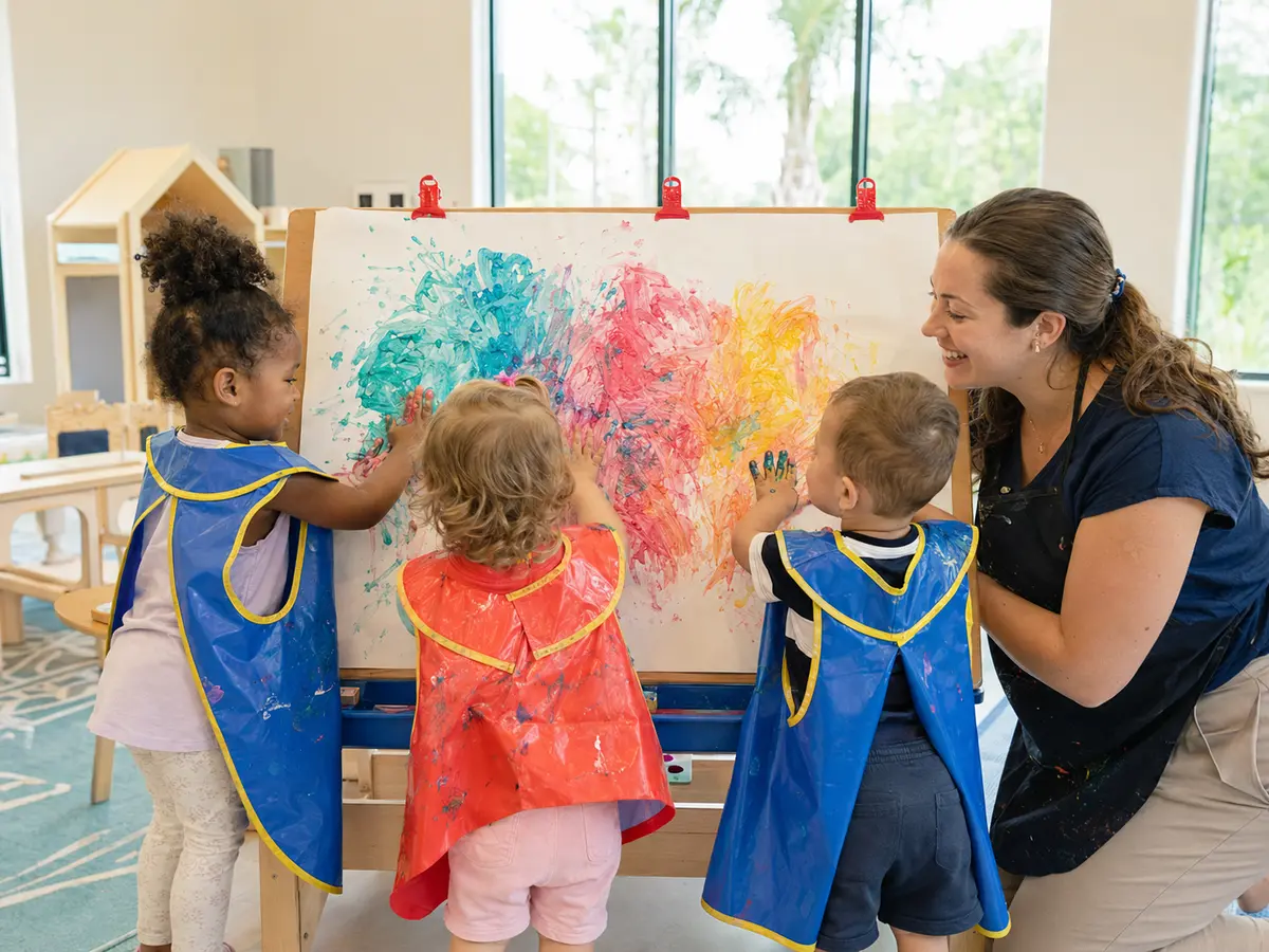 Two-year-olds enjoying a colorful classroom painting activity